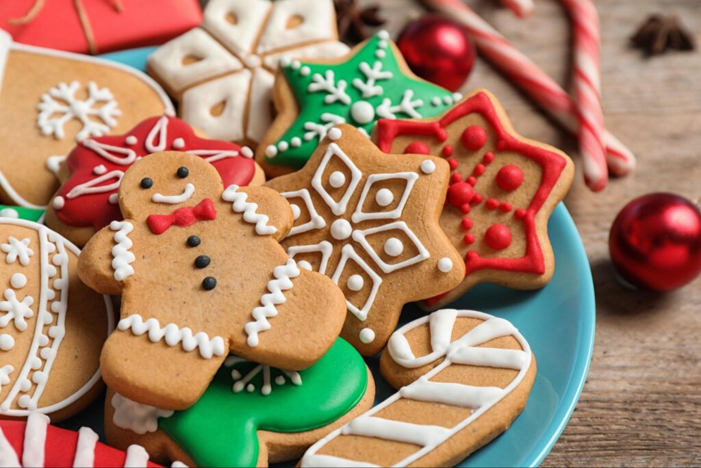 Colorful holiday cookies, including gingerbread men, snowflakes, and candy canes, on a blue plate, representing braces-friendly treats for families in Homer Glen, promoting Booth Orthodontics' community-focused orthodontic care.